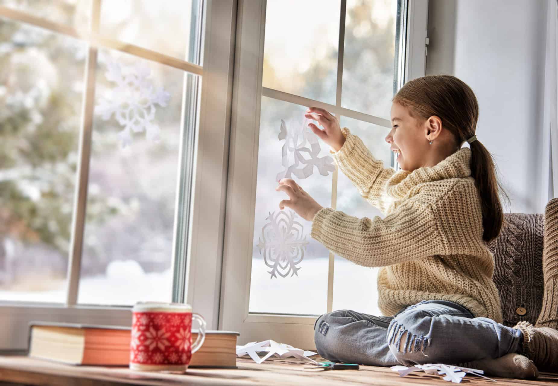 girl putting christmas decorations on modern window