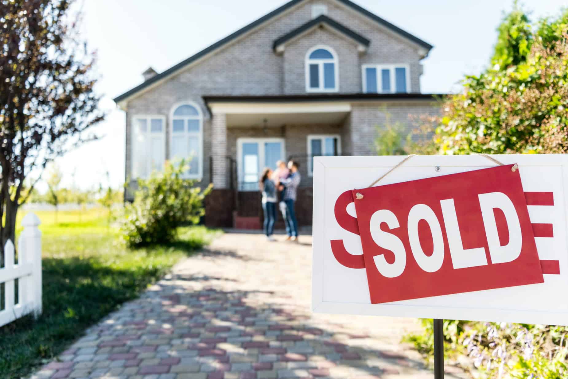home with sold sign with family and house in background