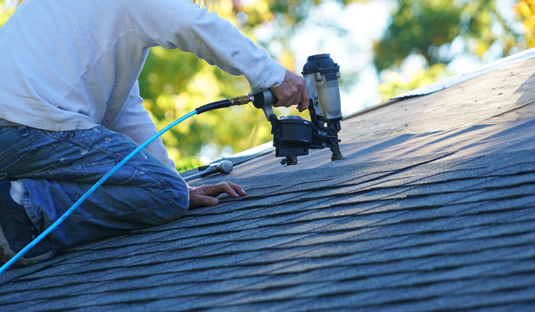 worker repairing roof with trees in background