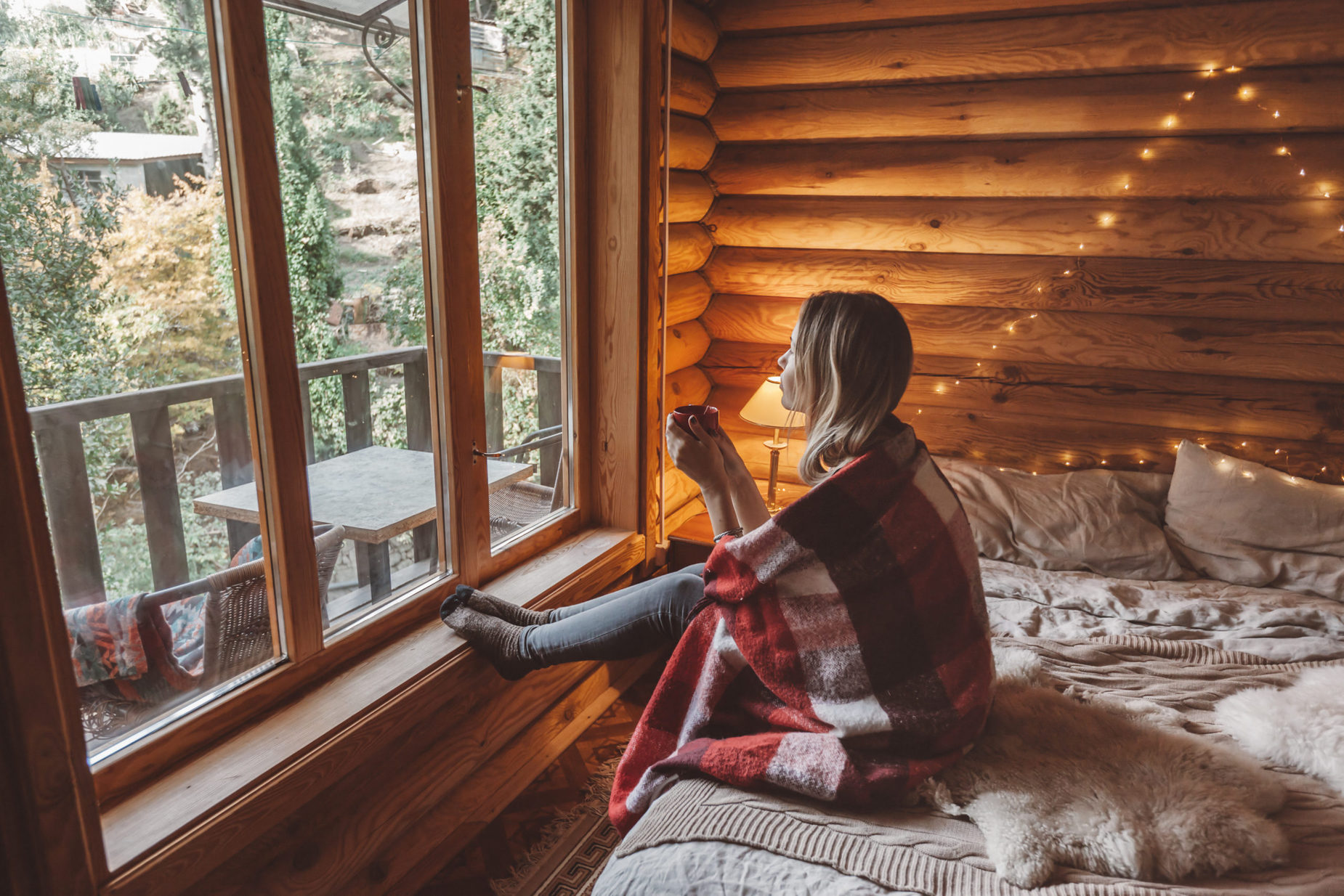 woman sitting on bed looking through window