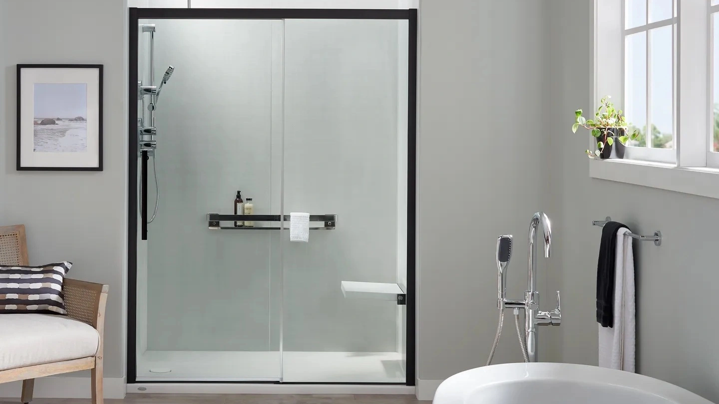 A recessed walk-in shower with black features and silver fixtures and a standalone bathtub
